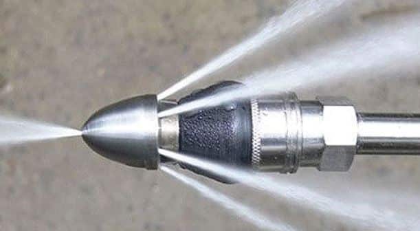 Close-up of a high-pressure water jet nozzle spraying multiple streams of water in different directions.